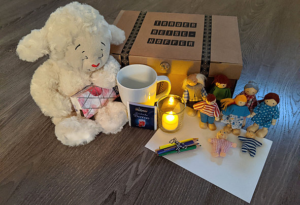 Trauerreisekoffer mit Kuscheltier, Kerze, Tasse und Figuren
