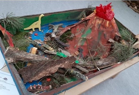 Diorama eines Schulprojekts mit Vulkan, Dinosauriern und Naturmaterialien